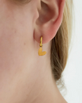 Load image into Gallery viewer, oorbellen in oren. goudkleurige oorbellen met hartjes hanger