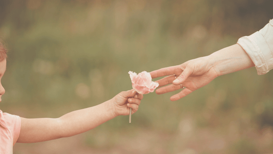 een kinderhand die een moederhand een bloemetje aangeeft