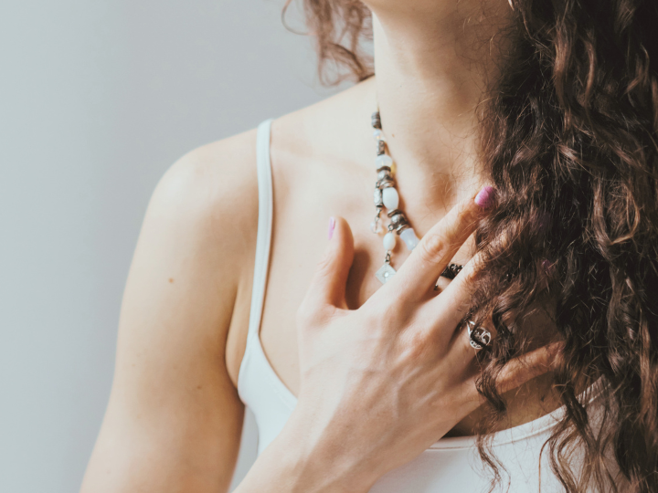 Vrouw met hand op haar hart, een stil moment van voor jezelf kiezen en luisteren naar zichzelf.