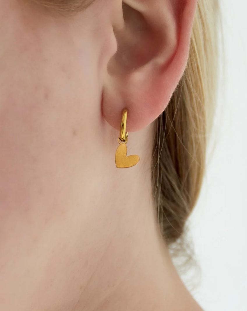 oorbellen in oren. goudkleurige oorbellen met hartjes hanger