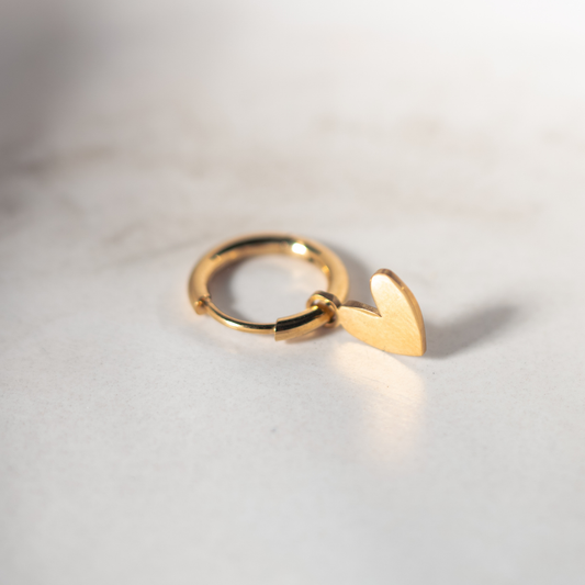 Gouden Lief Leven oorbel met hartvormige bedel op een zachte marmeren achtergrond.